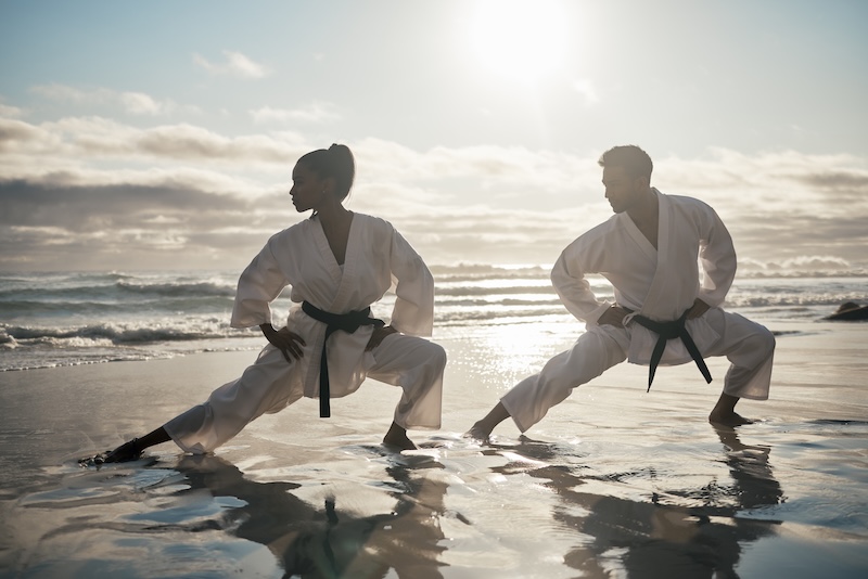 Två personer på strand som utövar kampsport